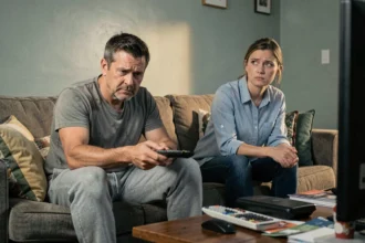Couple sur un canapé avec distance émotionnelle, homme désengagé regardant la télécommande et femme frustrée détournant le regard