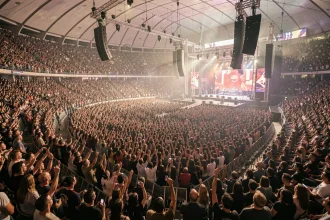 Vue panoramique depuis les gradins supérieurs de la salle Bercy lors d'un grand concert rock, foule immense dans la fosse et les sièges